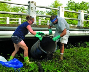 Sarah and Daniel Solomons lug an ironic item up from the debris – a 50-gallon trash can – pulled from McCoys Creek