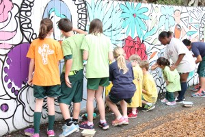 Fifth-grade students at St. Paul’s Catholic School assist pre-kindergarten students fill in the outlines of a mural.