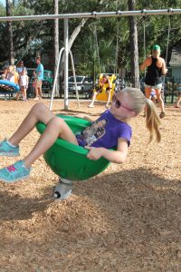 John Stockton Elementary School student Carolyn Campbell, 6-1/2, takes a twirl in a bucket ride. “I love it!” she said about the new KOMPAN equipment at the playground on St. Johns Avenue.