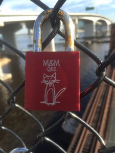 Engraved locks hang on a chain link fence on the pedestrian bridge underneath the Acosta Bridge near Brooklyn.