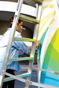Cecilia Lueza, an artist from South Florida, spray paints a mural on a skyway column on Hogan Street April 4.