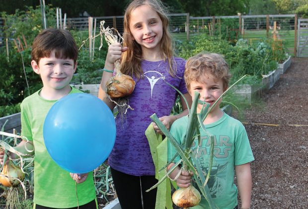 Mary Bullock Wedekind with her brothers, Bo and Tucker, show off onions planted by their uncle, Kirk Wedekind.