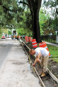 A worker measures a length of curbing on Park Street as part of a drain replacement project.