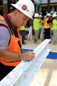 Paulino Navarro of DPR Construction’s framing and drywall division signs a beam for Baptist MD Anderson Cancer Center.
