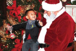 Santa listens to an enthusiastic little boy share his Christmas wish list at the the 3rd Annual Jolly Christmas at St. Nick’s.
