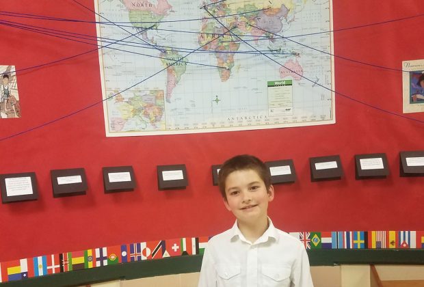 Third-grade student Jacob Seal with an exhibit that answers the question “How do children from other countries access books?”
