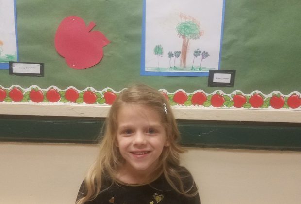 Kindergartener Annabel Voigt, poses in front of an exhibit all about plants.