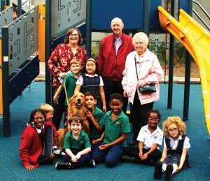 Morning Star Catholic School Principal Jean Barnes with Warren and Joanne Powers on the new playground with students and Nova, the service dog.