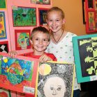 Micah Hall, third grade, gets some help from his big sister, Natalie, holding his artwork.