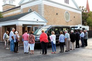 Family Promise supporters gather in circle around the bus to bless it.