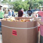 Paul Seymore and Bob Lowry, members of the Men’s Garden Club, fill bags with potatoes for local food banks.