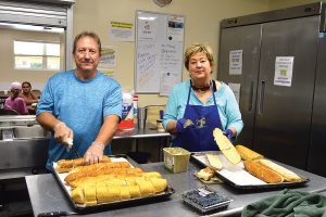 Gary Fregeau and his wife, Karen, of Our Lady Star of the Sea Catholic Church, prepare bread for lunch at Mission House.