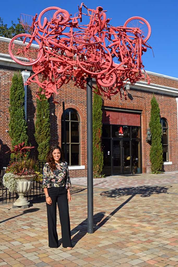 Tiffany Ash, business manager of the design and development firm AshCo, stands beside a whimsical sculpture designed by her sister, Nicole Ash, who also works for AshCo.