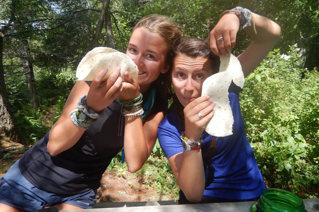 Sophie Hojnacki holds an intact tortilla, while Marley Barton (right) shows off a “defective” tortilla shell during an Outward Bound meal.