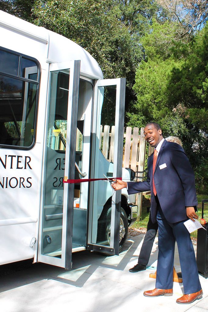 Emmanuel Fortune, program director at The Community Foundation for Northeast Florida, cuts the ribbon for the new passenger bus.