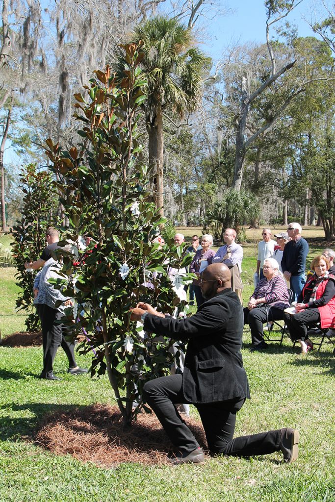 Jonathan Joseph kneels to affix a commemorative leaf to a magnolia tree planted on Valentine’s Day in Love Grove.