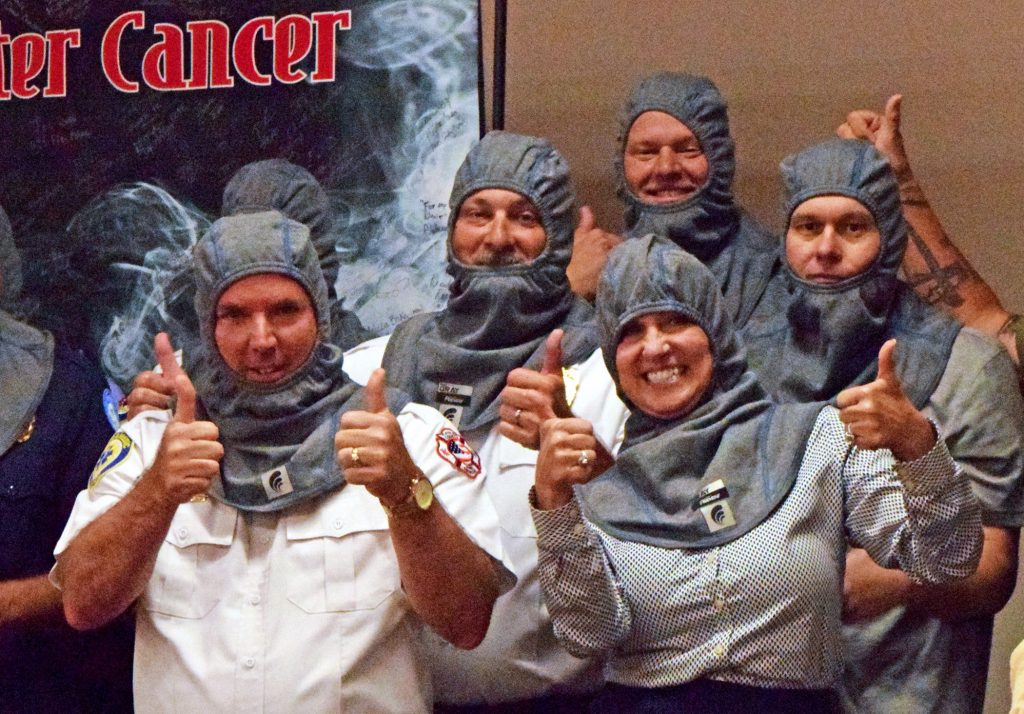 Flagler County Fire Rescue Fire Chief Petito, Rotary Club of Flagler County President Cindy Evans join Flagler firefighters in showing off their new cancer-preventing hoods.