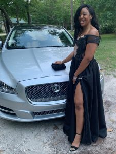 Still wearing her hospital ID bracelet and showing off a bruised knee, Nekayla Hyles poses in the prom dress her grandmother made next to the Jaguar which a Mayport employee loaned to her family for a week.