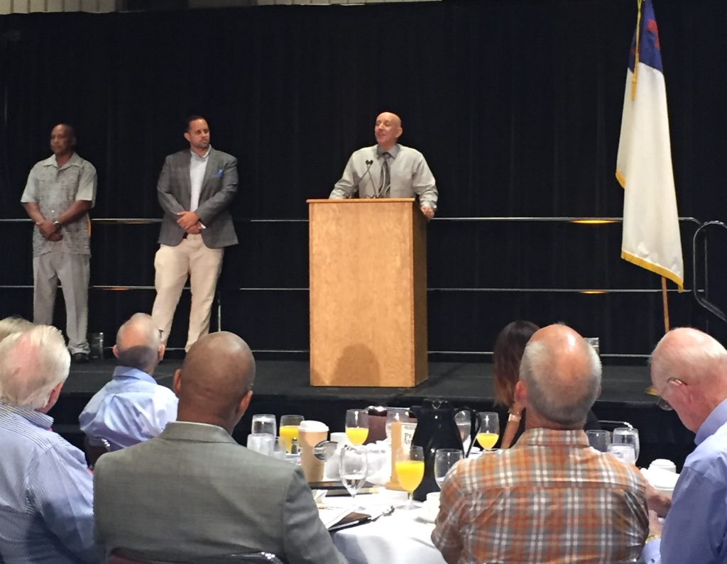 Jeff Green, Mark Krancer and Steven Medlin at the podium at the annual Prisoners of Christ breakfast June 25.
