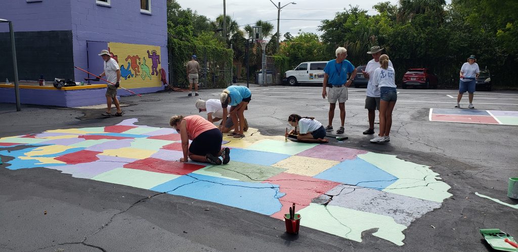 Volunteers repaint a map of the United States on the blacktop at Sanctuary on 8th Street.