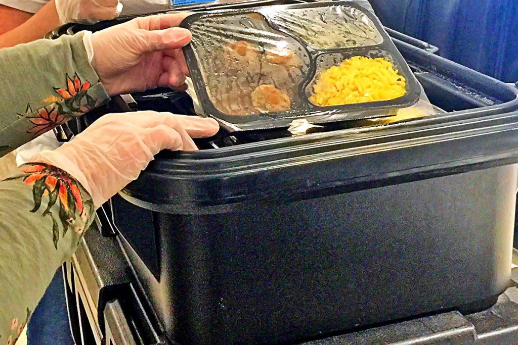 A staff member at Cathedral Towers distributes ready-to-go diners to the residents.