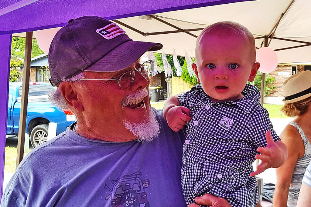 Michael Swann holds great grandson Cason James Head, whose mother is Haley Trimble Head, at an outdoor event.