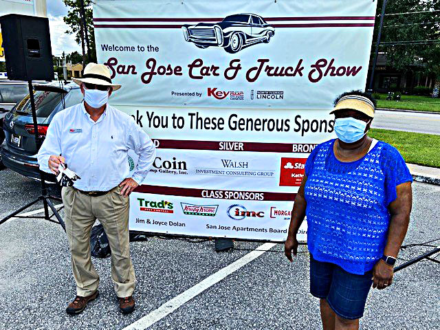 Eric Thompson, a sales manager with Key Buick GMC Hyundai Genesis, gets together with Alma Ballard, executive director/management agent of Family Housing Management Company for a photo in front of the show’s sponsor banner.