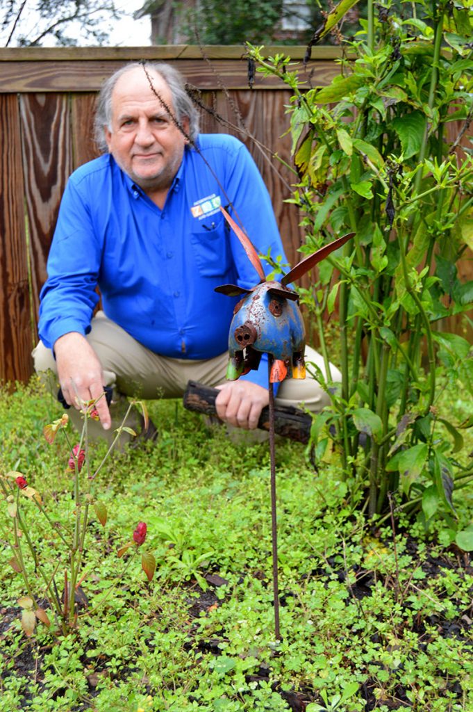 Tony Vecchio poses with the flying pig that oversees his butterfly garden