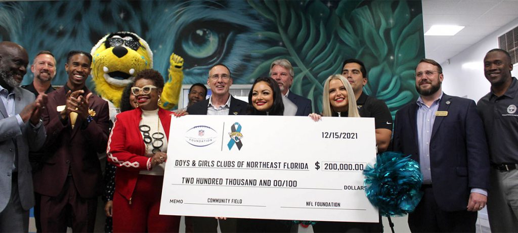 People and Jaguars mascot clapping and posing with $200,000 donation check