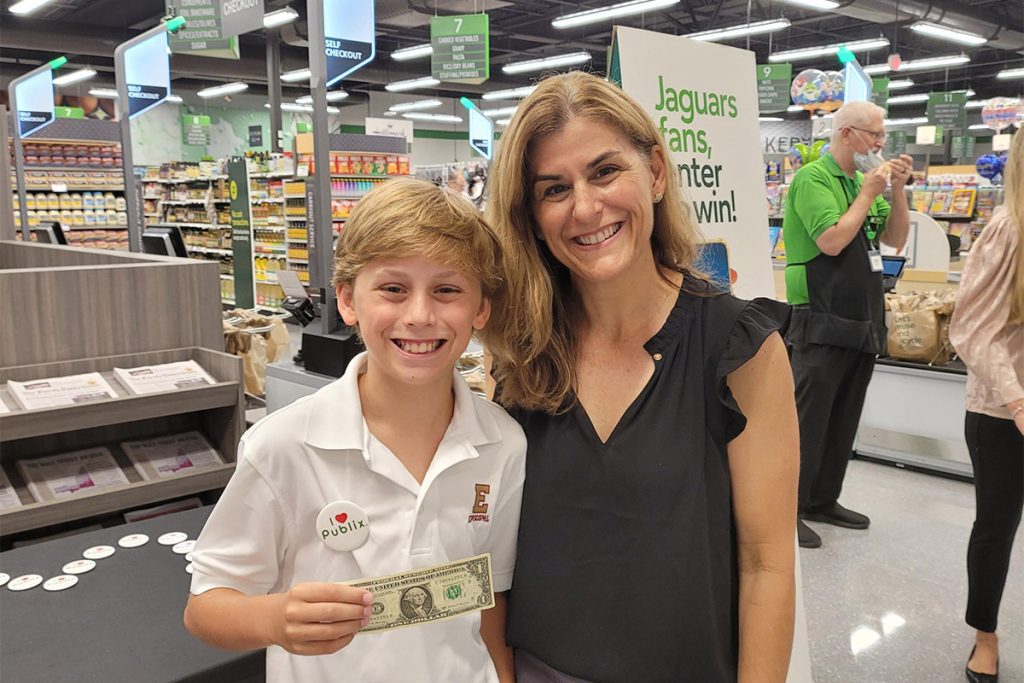 smiling woman and boy holding one dollar bill