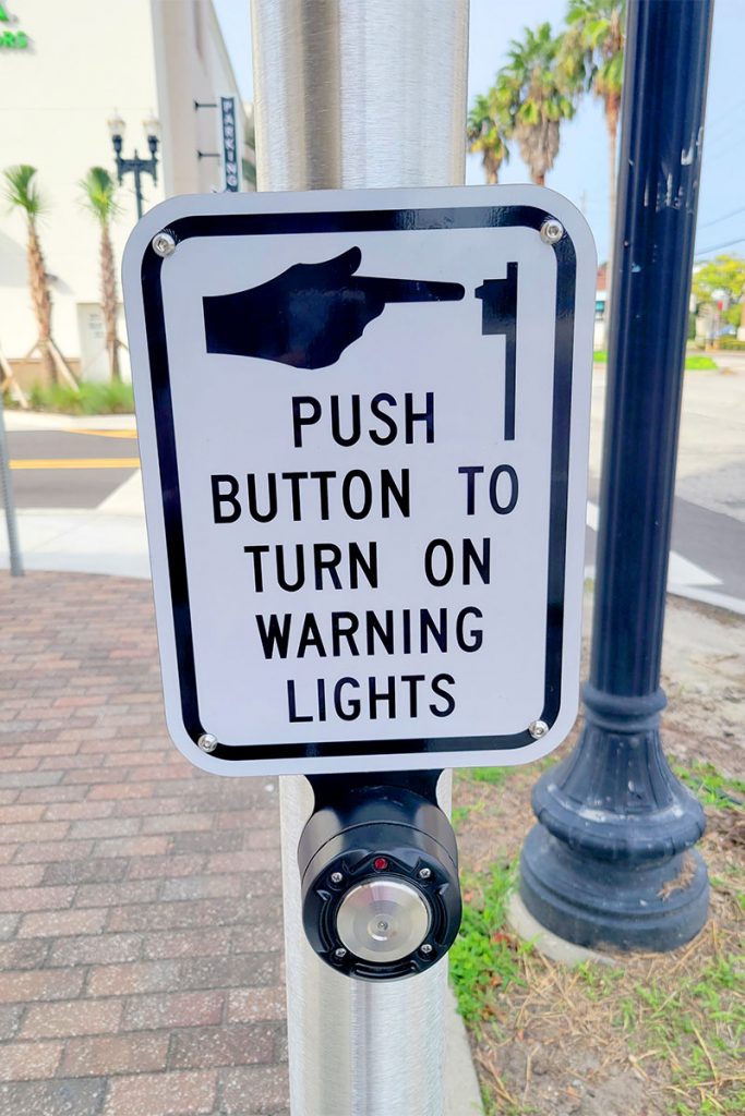 sign reading "Push button to turn on warning lights"
