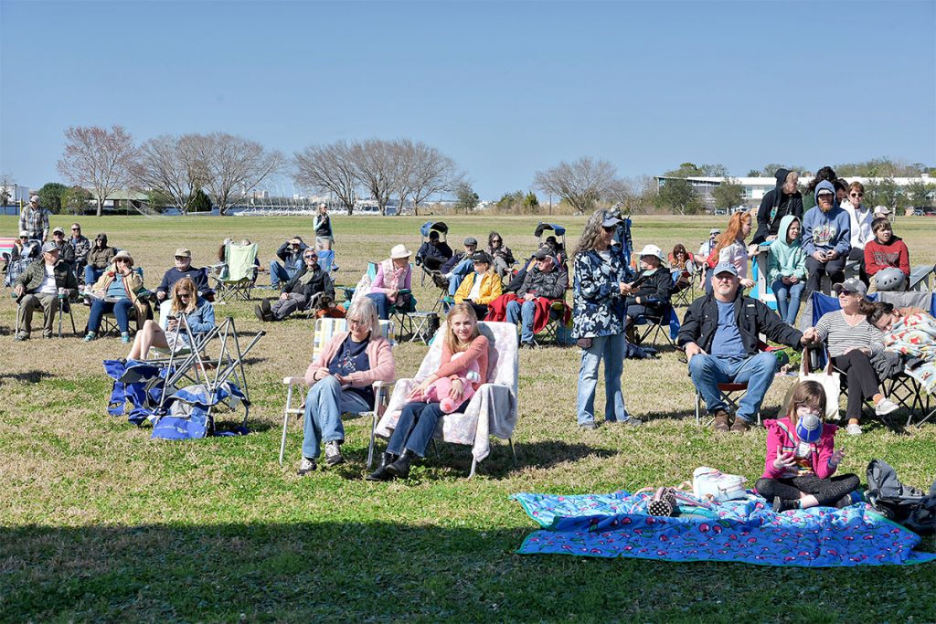 crowd of concert-goers sitting outside in the sunlight