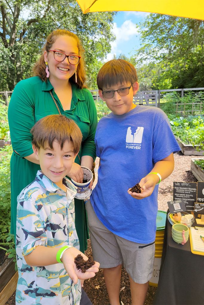 Tiffany Bess from Apple Rabbit Compost helps Samuel and his brother Andy get their hands dirty for the Garden Tour scavenger hunt.