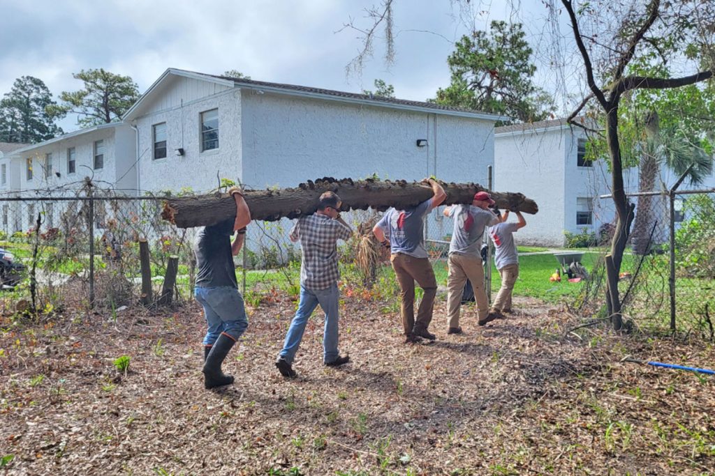 Team Rubicon Greyshirts carry a fallen tree out of the historic cemetery at St. Nicholas Bethel Baptist Church.