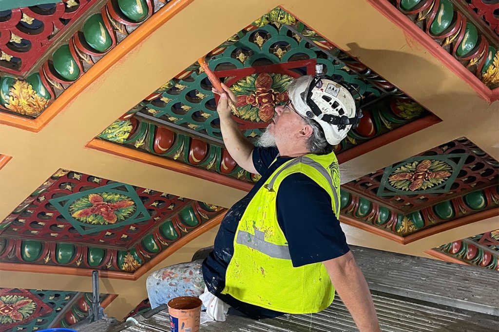 A painter painstakingly restores ceiling carvings to their original glory atop scaffolding erected inside the Florida Theatre.