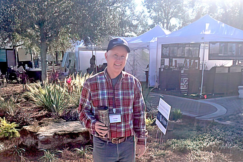 man in flannel shirt smiling at art festival
