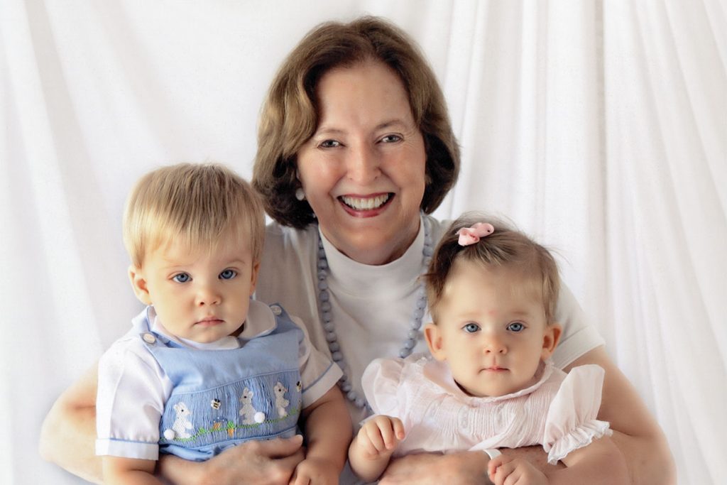 Nancy smiling and holding two babies