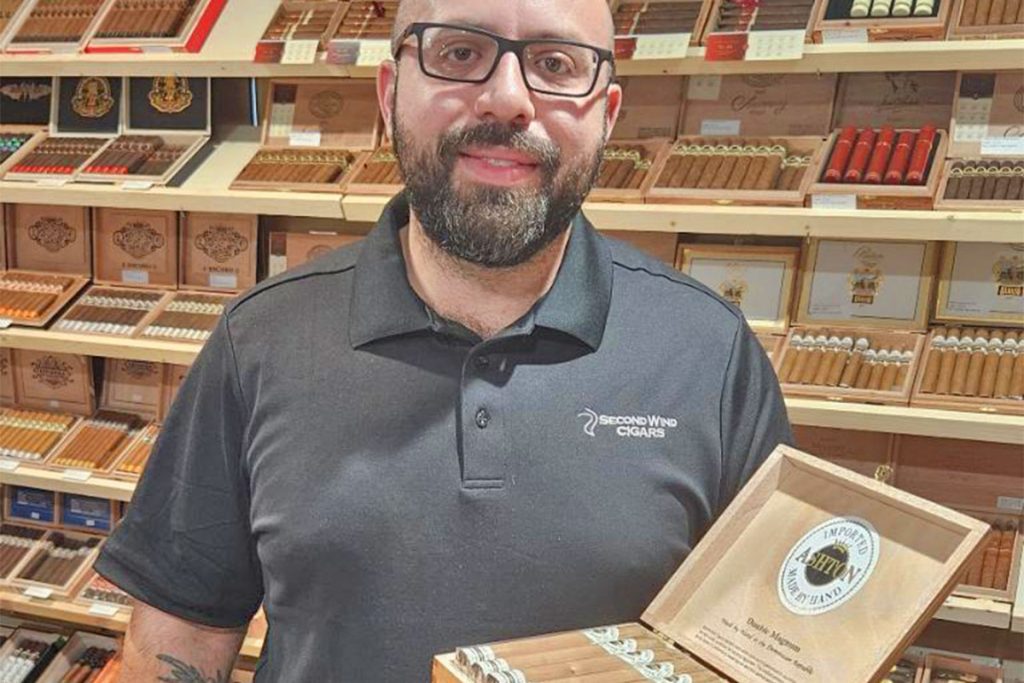 Owner Peter Jaghab stands before his inventory of premium cigars at Second Wind Cigars in San Marco.