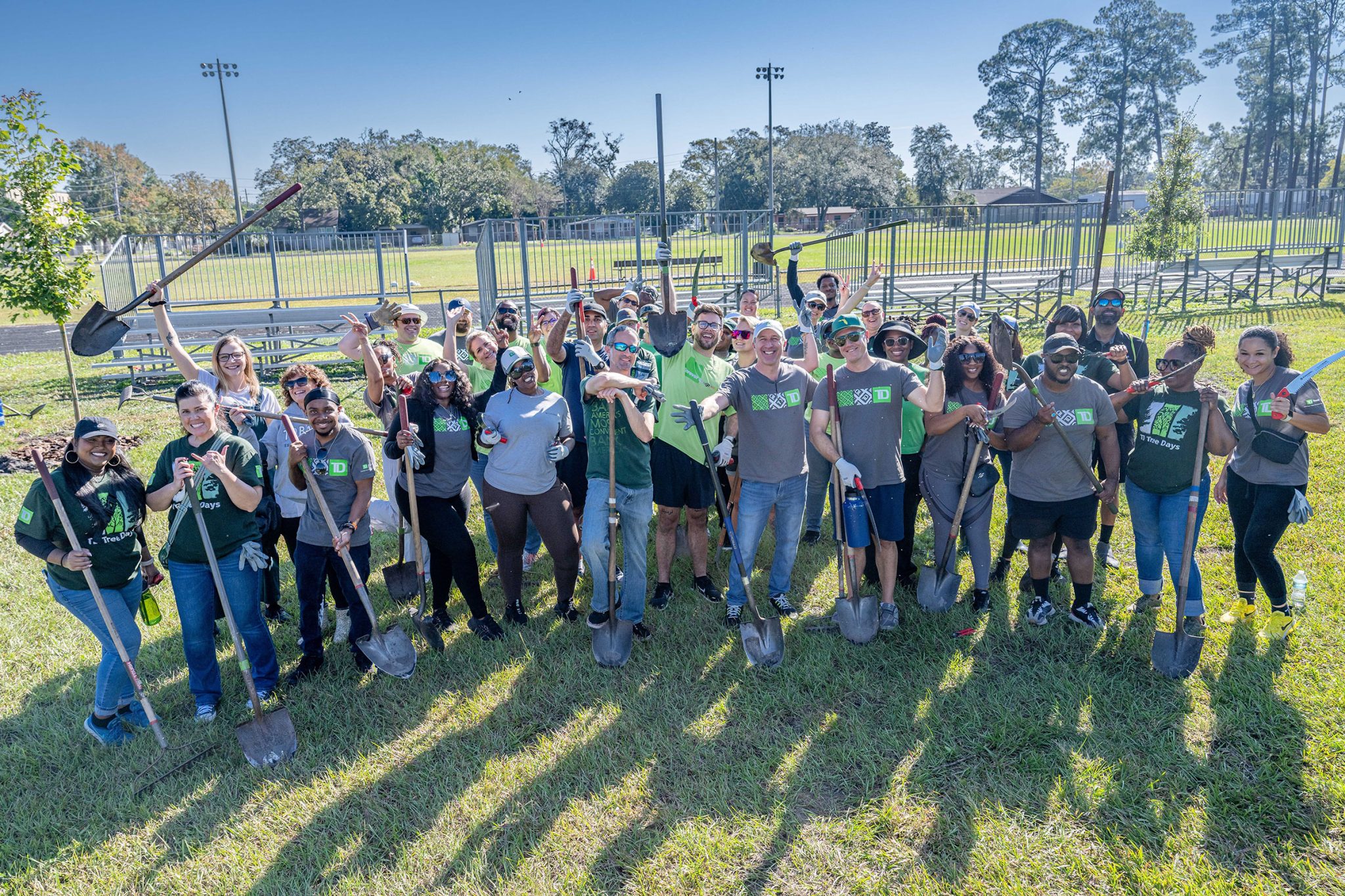 photo of people at the park smiling and holding shovels