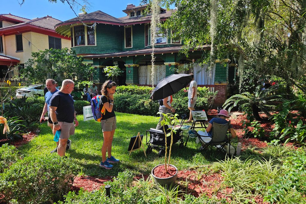 Patrons approach a plein air painter at the Green House, one of the tour stops.