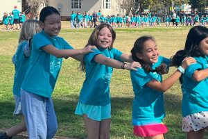students walking and smiling in a line with hands on each others' shoulders
