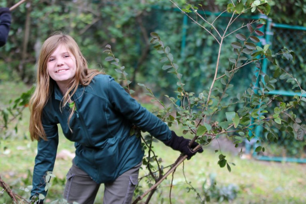 girl smiling and cleaning plant debris