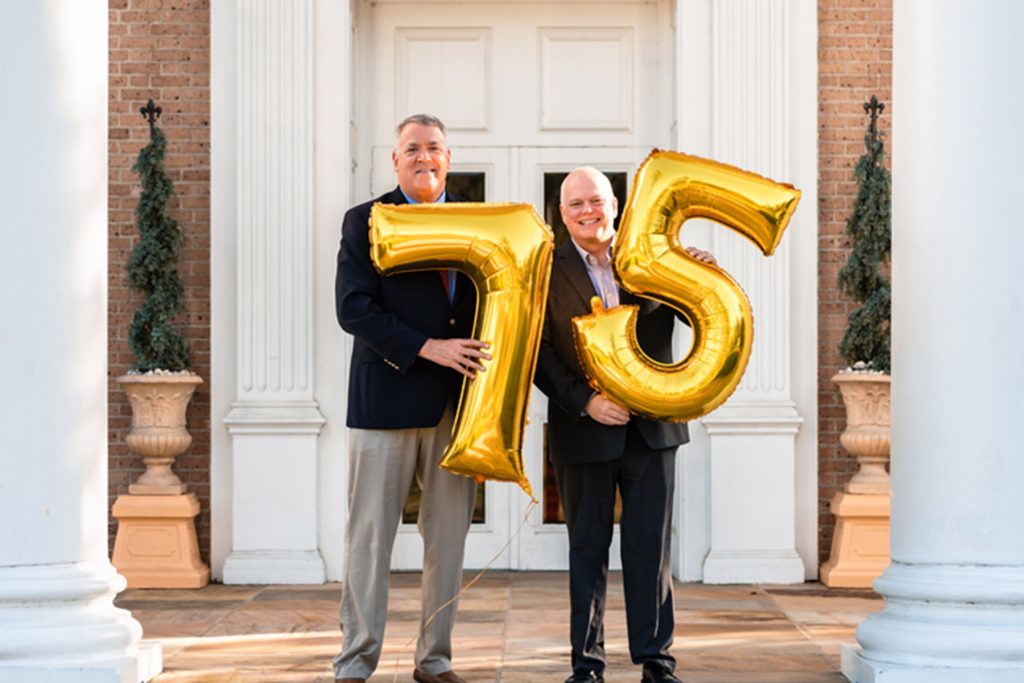 pastors at entrance of Southside Methodist Church, holding gold balloon numbers 75