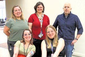 Bill Britton Murray Hill Library team members Kelsey Growth, Ericka Ricker and Doug Fair stand behind Maeve Coen and Kayleigh Schwend at a luncheon for library staff during National Library Week.