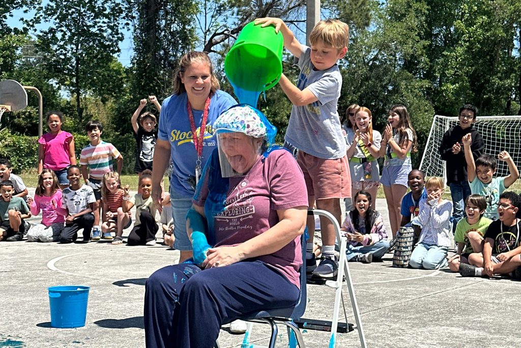 Stockton first grader Antonio C. dumps a bucket of slime on Principal Stephanie Brannan.