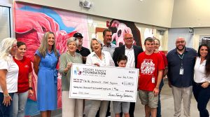 Dignitaries and stakeholders during the July 9 check presentation The Arc Jacksonville President and CEO Kari Bates, The Arc Jacksonville Board Members Bernadette Moran and Kit Thomas with The Tesori Family Foundation’s Paul Tesori with son Isaiah, City of Jacksonville’s Director of Administrative Services Richard Reichard, PAWS Program graduate/ACPS employee AQidan Balzli, ACPS Division Chief Michael Bricker, and Michelle Tesori.