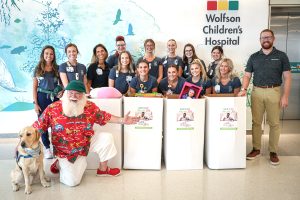 Santa and Jude, the facility dog with Wolfson Children’s Hospital Family Support Services team members and Phil Porter Jr. from Subaru of Jacksonville, showcasing toys collected at Subaru of Jacksonville’s dealership throughout the month of July 2024.