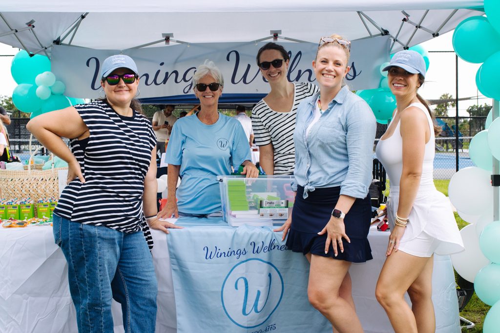 smiling women at Winings Wellness tent at ECHO Fair