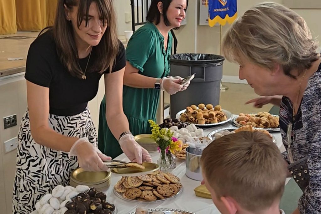 Parent volunteers Joanna Massey and Victoria St. Clair Broering serving families at the reception.