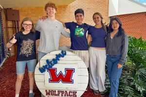 students smiling with wooden "Wolfpack" sign